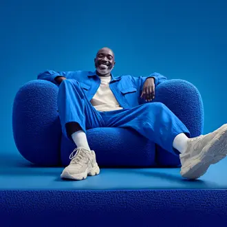 Person in blue fashion seated in an oversized blue chair