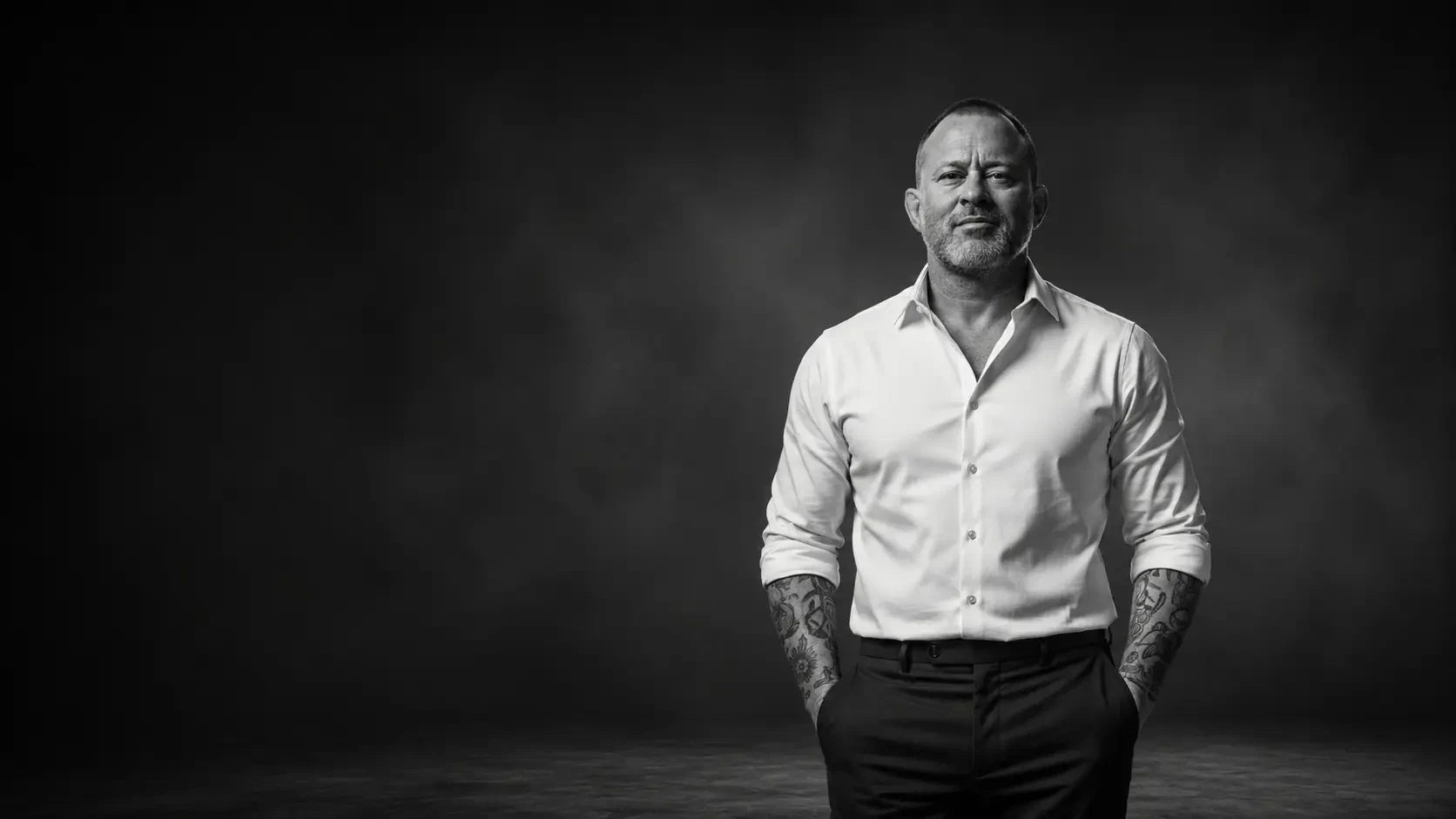 Tobin Dorn standing with crossed arms in a black and white studio portrait